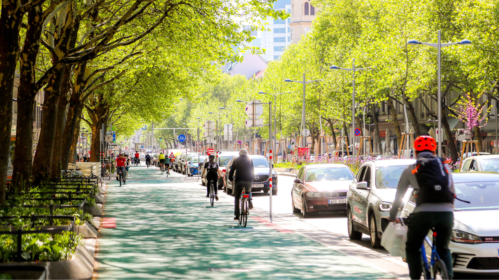 Radfahrende auf einem breiten, gut ausgebauten Radweg in Wien, umgeben von urbaner Infrastruktur und Grünflächen. Das Bild symbolisiert die Radoffensive Wien 2021–2025 mit sicherer und komfortabler Radinfrastruktur für den Alltagsverkehr.